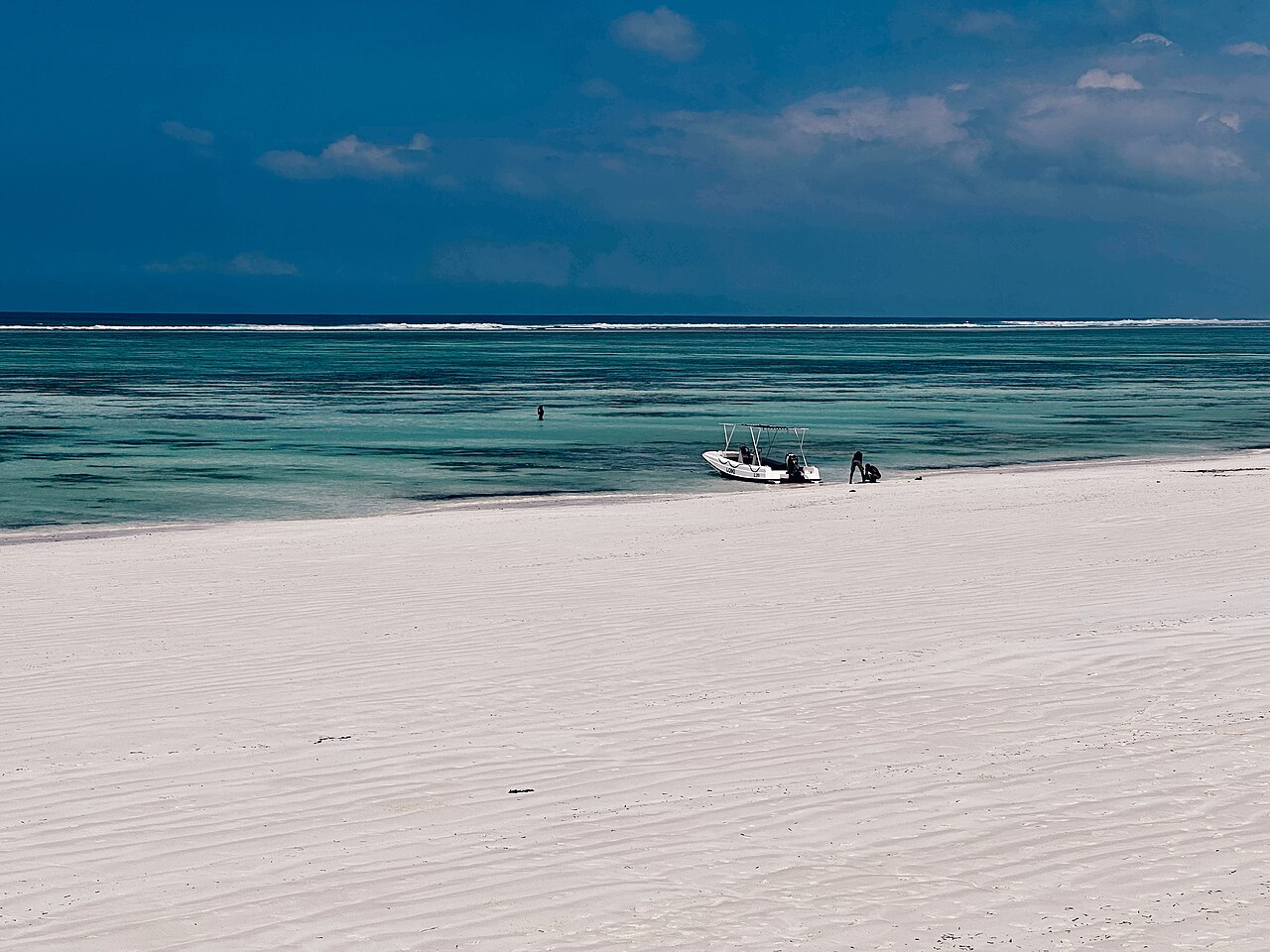 Sand, shallow water and a small boat at Matemwe Beach